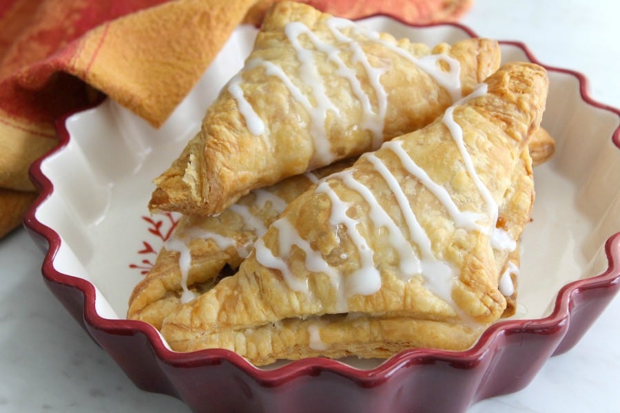 Your favorite pie made into a hand held dessert with these Pumpkin Pie Turnovers! It only taste a little bit of time and a few ingredients! Pumpkin Pie Turnovers stacked in red bowl with orange napkin