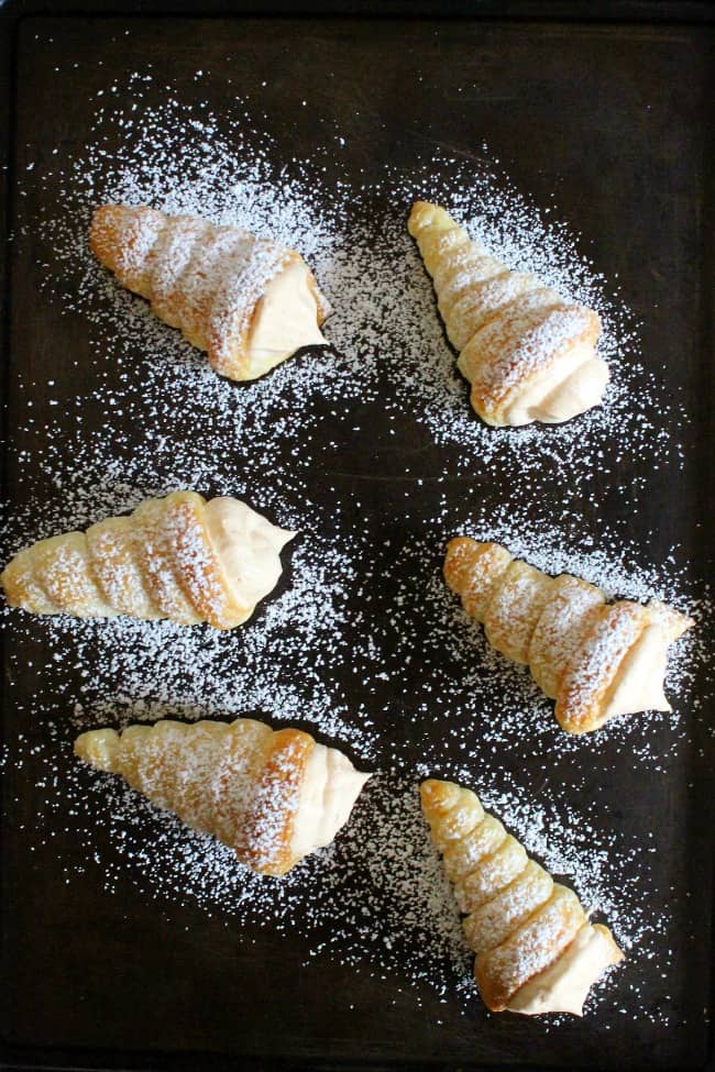 Pumpkin Cream Horns are a simple dessert that’s perfect for the season! You’ll love the light and fluffy filling full of delicious spices! overhead view of cream horns on sheet pan.