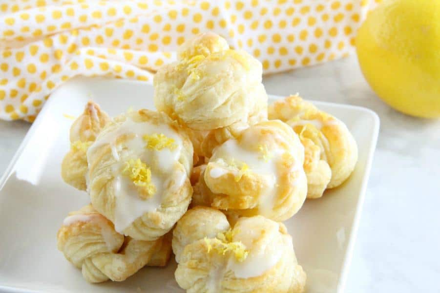 These Puff Pastry Lemon Knots are super easy to make but full of lemon citrus flavor! Perfect to make for a simple dessert! Puff Pastry Lemon Knots on white plate