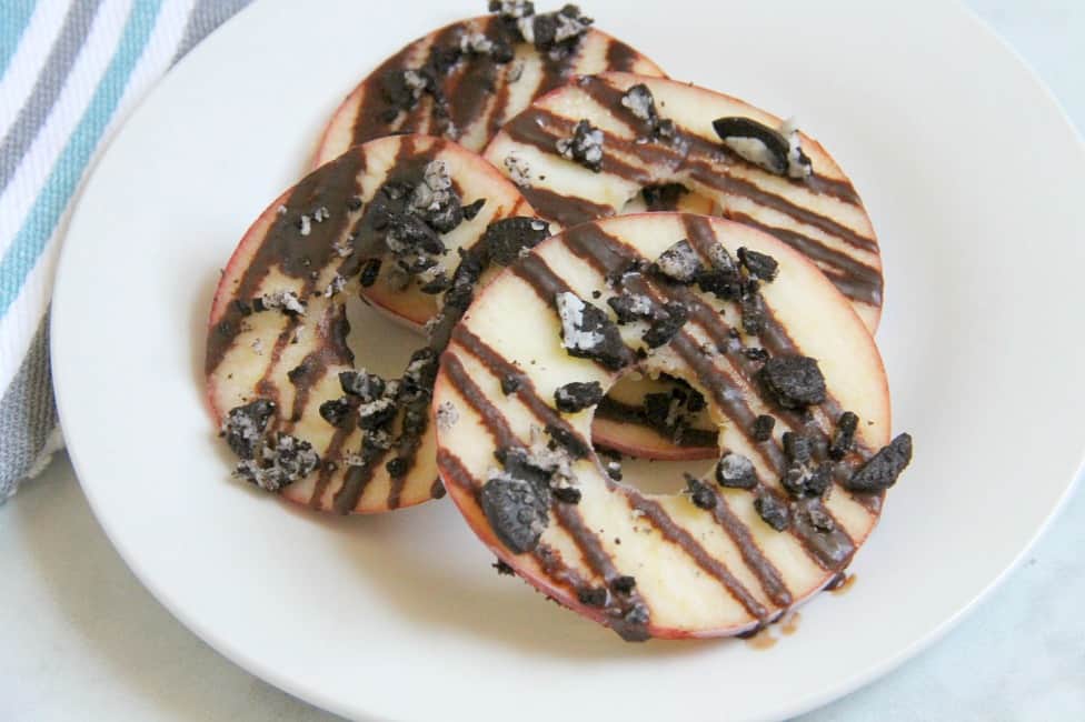 Indulging in this back to school treat for kids by adding fruit and dark chocolate to these Chocolate Oreo Apple Donuts! Your kids will be jumping for joy! | The Bitter Side of Sweet #SnackTimeDelight #ad #oreo #chocolate #apples Chocolate Oreo Apple Donuts on white plate