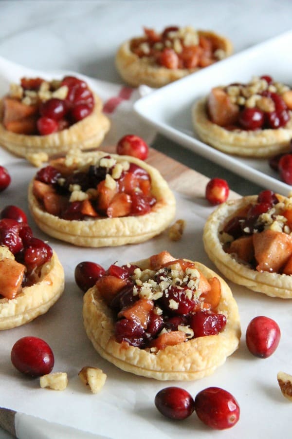 These Cranberry Apple Walnut Tarts would be the perfect addition to your holiday dessert table! Perfect for when you want to make individual desserts! | The Bitter Side of Sweet #cranberry #walnut #puffpastry #apple Cranberry Apple Walnut Tarts on parchment paper