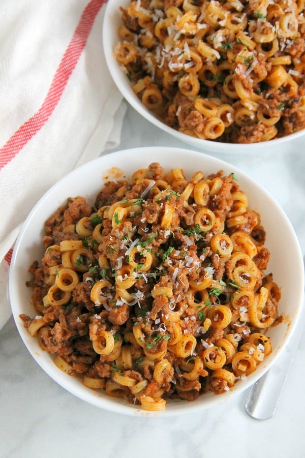 Easy Homemade Spaghetti O's are a family favorite! Made with tomato sauce, spices and ground beef. Fun large ring pasta noodles completes this meal! | The Bitter Side of Sweet #farmtocan #pasta #groundbeef #30minutemeals Homemade Spaghetti O's in white bowl