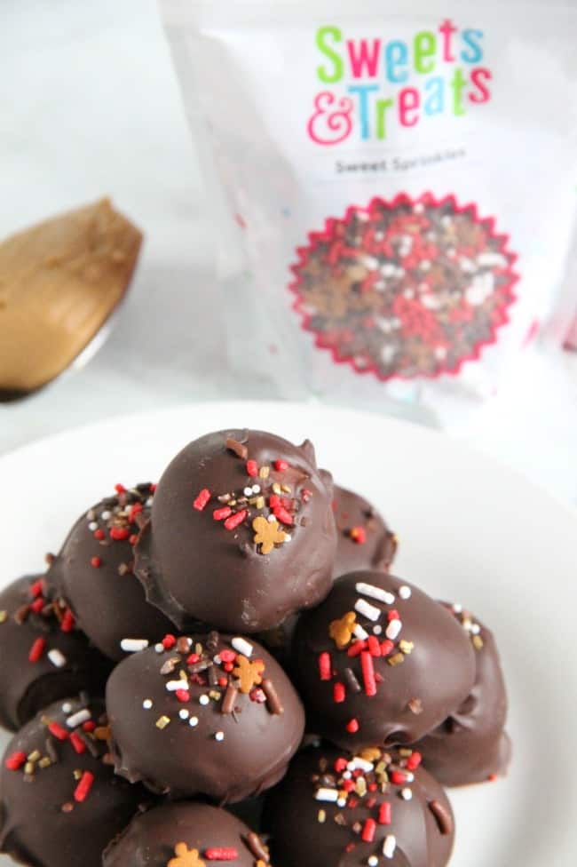 These Cookie Butter Balls are a twist on the classic candy, peanut butter balls! You will love the creamy texture of the cookie butter covered in semi sweet chocolate! | The Bitter Side of Sweet #christmassweetsweek #ad #chocolate #candy Cookie Butter Balls on white plate