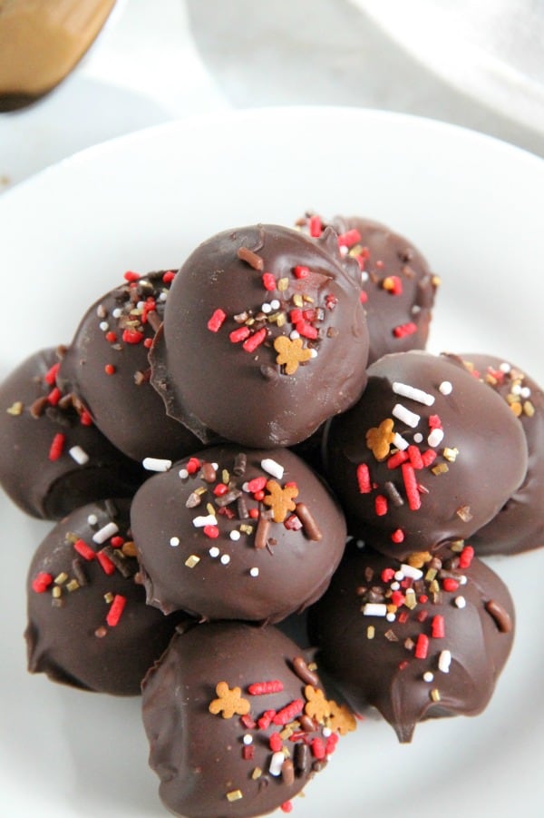 These Cookie Butter Balls are a twist on the classic candy, peanut butter balls! You will love the creamy texture of the cookie butter covered in semi sweet chocolate! | The Bitter Side of Sweet #christmassweetsweek #ad #chocolate #candy Cookie Butter Balls on white plate