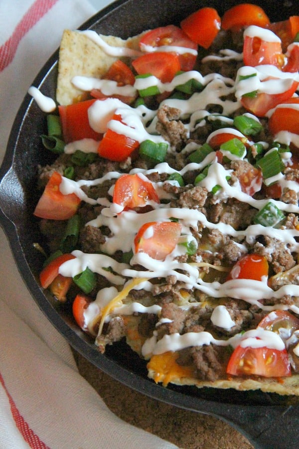 Taco Skillet Nachos are the best kind of party food! All of your favorite flavors for tacos topped onto a bed of tortilla chips for a delicious appetizer! | The Bitter Side of Sweet #gameday #appetizer #taco Taco Skillet Nachos in black skillet