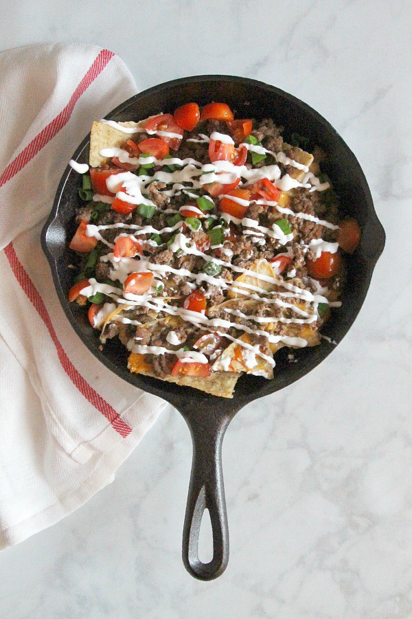 Taco Skillet Nachos are the best kind of party food! All of your favorite flavors for tacos topped onto a bed of tortilla chips for a delicious appetizer! | The Bitter Side of Sweet #gameday #appetizer #taco Taco Skillet Nachos in black skillet