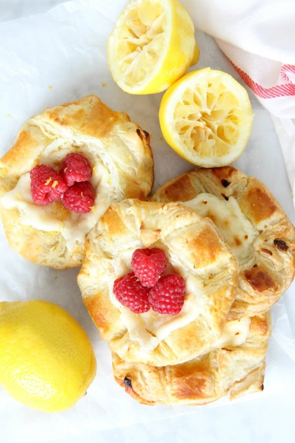 Start your day with a Lemon Raspberry Danish! You'll be so glad you did. With a warm cheese filled center and butter pastry this is perfection! Lemon Raspberry Danish on parchment paper