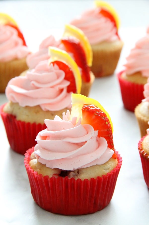 These Strawberry Lemon Cupcakes are a made from scratch cupcake! So moist with a little strawberry in each bite topped off with cream cheese frosting! | The Bitter Side of Sweet Strawberry Lemon Cupcakes with red cupcake liner on white background
