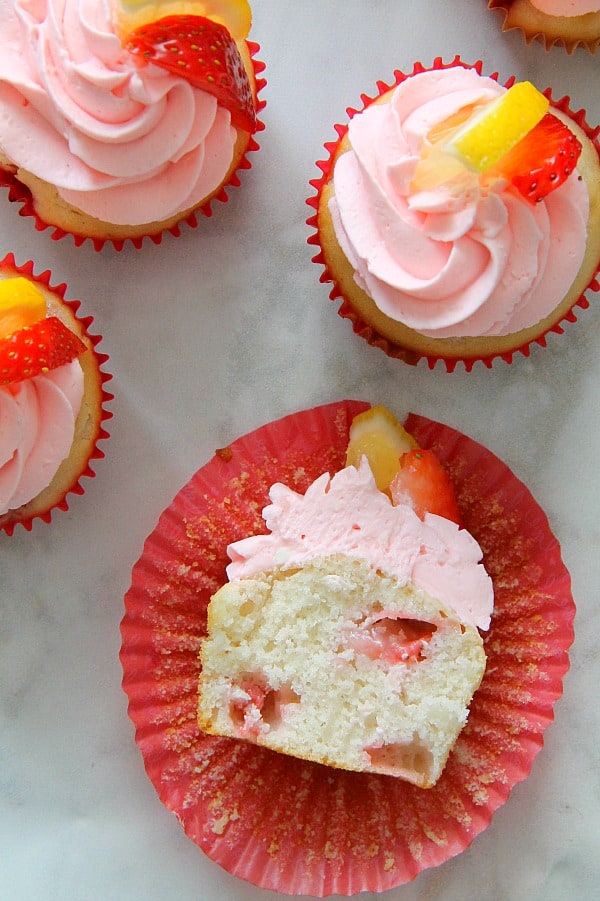 These Strawberry Lemon Cupcakes are a made from scratch cupcake! So moist with a little strawberry in each bite topped off with cream cheese frosting! | The Bitter Side of Sweet Strawberry Lemon Cupcakes with red cupcake liner on white background