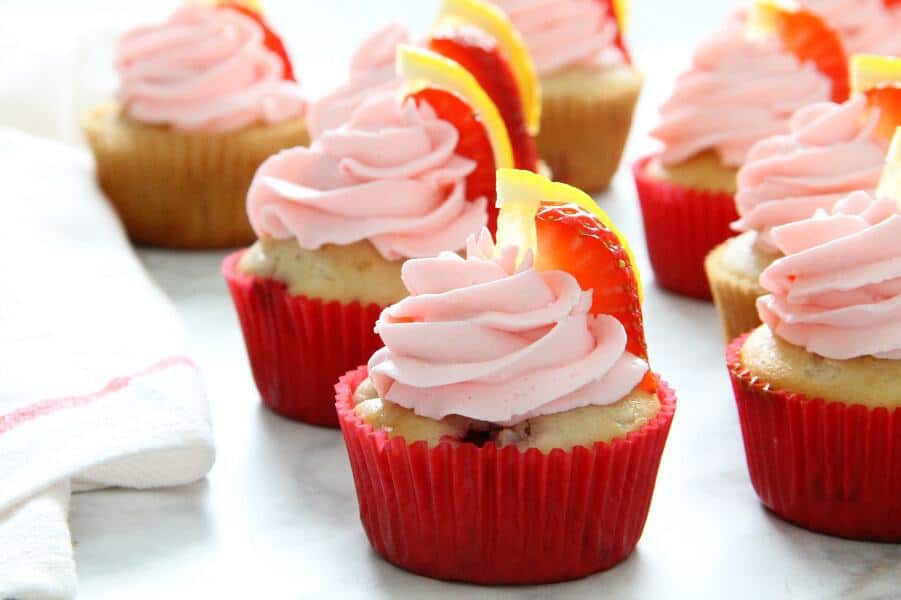 These Strawberry Lemon Cupcakes are a made from scratch cupcake! So moist with a little strawberry in each bite topped off with cream cheese frosting! | The Bitter Side of Sweet Strawberry Lemon Cupcakes with red cupcake liner on white background