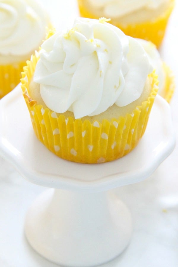 Moist and delicious Homemade Lemon Cupcakes topped with a homemade cream cheese frosting with added lemon zest. Perfect for any day of the week! | The Bitter Side of Sweet Lemon Cupcakes on white plate