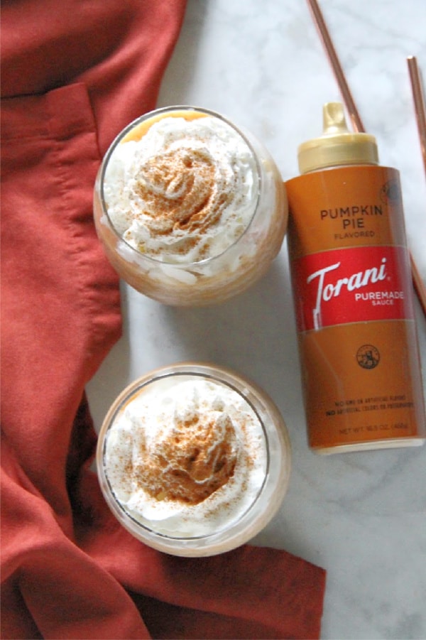 With just a few ingredients you can make your own coffee shop favorite drink! This Easy Pumpkin Frappuccino has all of the flavors of fall! Easy Pumpkin Frappuccino in glass