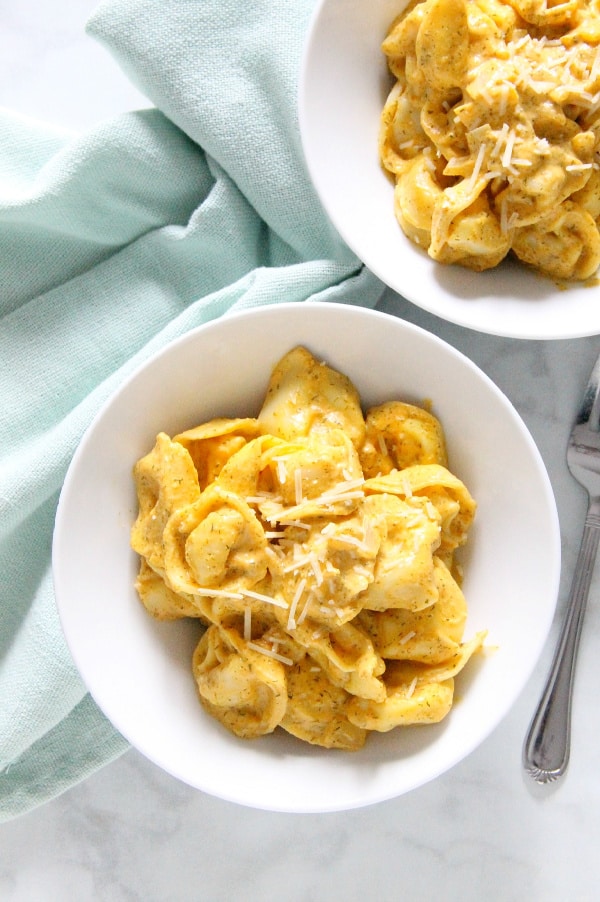 Creamy Pumpkin Tortellini is the simple supper your fall menu needs. This light, creamy sauce has just the right flavor profile to match up to pumpkin! Creamy Pumpkin Tortellini in white bowl