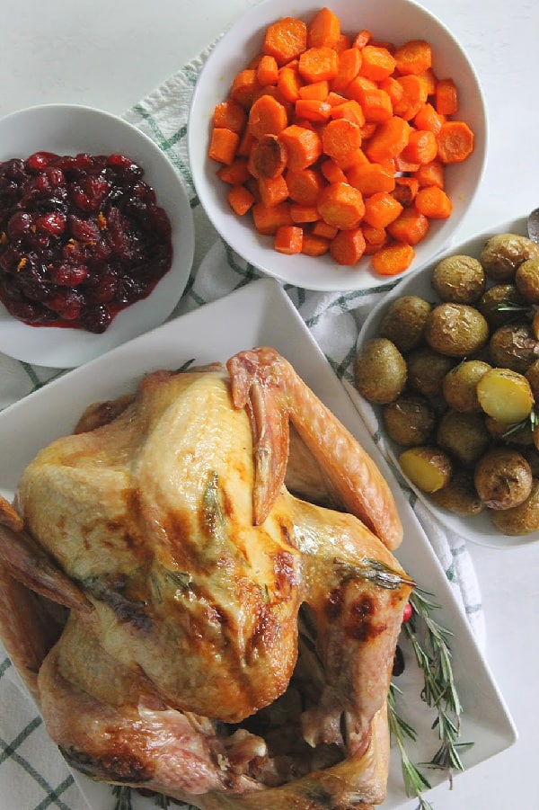 This Butter Rosemary Roasted Turkey will surely impress your guest! Cooked to perfection, this is moist buttery turkey with lots of flavor! | The Bitter Side of Sweet Butter Rosemary Roasted Turkey on white plate with full meal