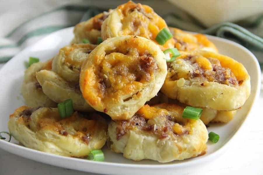 Puff Pastry Sausage Cheddar Pinwheels make a great game day snack. Filled with sausage and cheese they're great for dipping and so easy to make! | The Bitter Side of Sweet Puff Pastry Sausage Cheddar Pinwheels on white plate