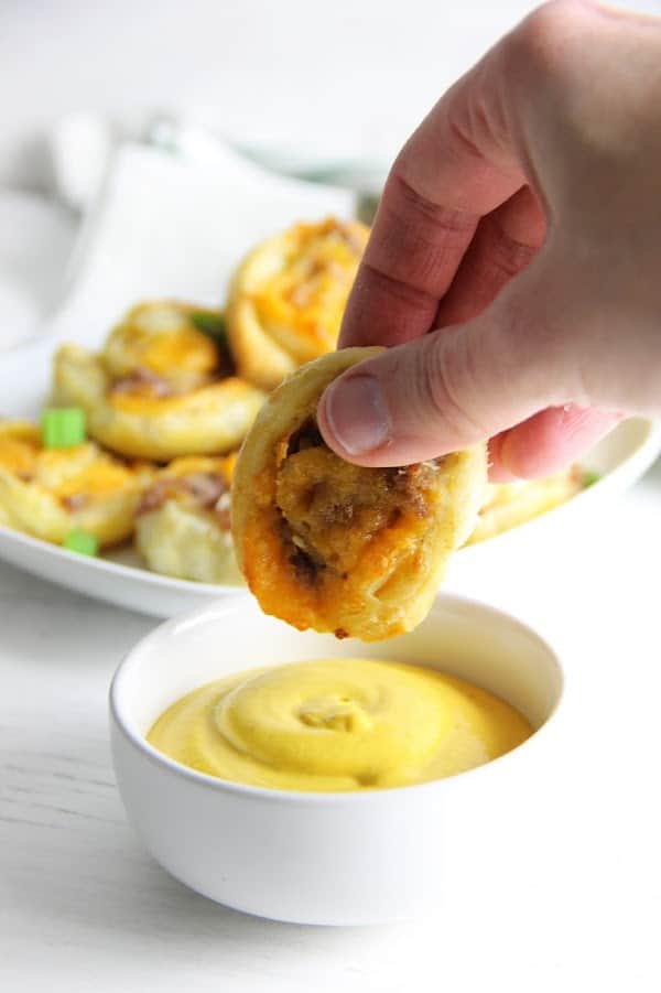 Puff Pastry Sausage Cheddar Pinwheels make a great game day snack. Filled with sausage and cheese they're great for dipping and so easy to make! | The Bitter Side of Sweet Puff Pastry Sausage Cheddar Pinwheels dipped into mustard