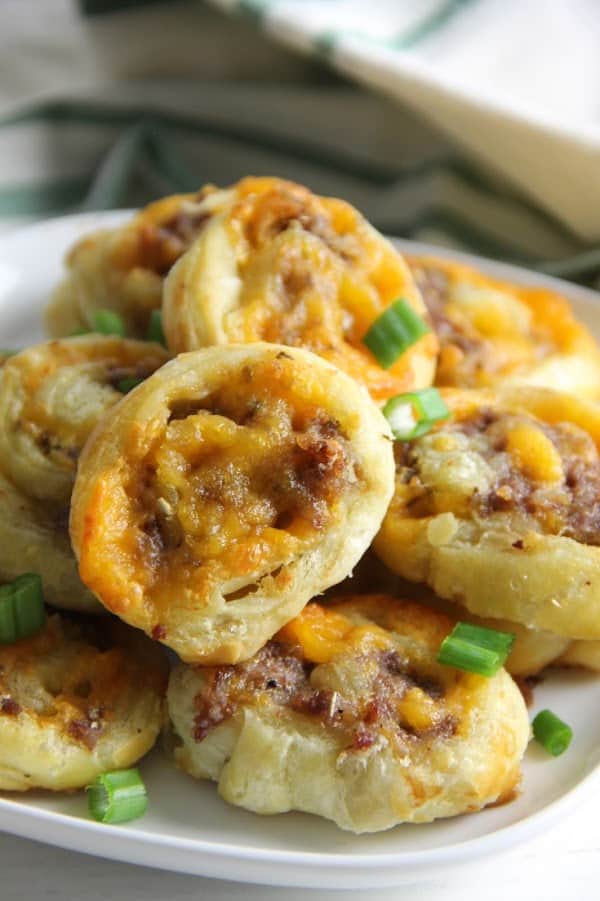 Puff Pastry Sausage Cheddar Pinwheels make a great game day snack. Filled with sausage and cheese they're great for dipping and so easy to make! | The Bitter Side of Sweet Puff Pastry Sausage Cheddar Pinwheels on white plate