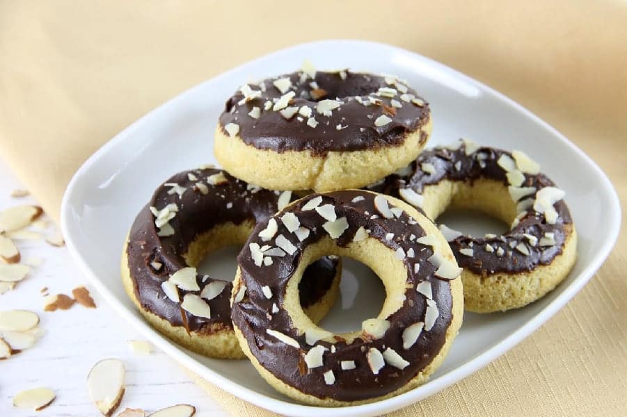 These Chocolate Glazed Almond Donuts are baked to perfect and topped with chocolate and almonds! They bake up in just about 10 minutes! | The Bitter Side of Sweet Chocolate Almond Glazed Donuts on white plate