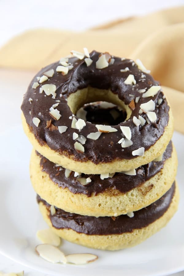 These Chocolate Glazed Almond Donuts are baked to perfect and topped with chocolate and almonds! They bake up in just about 10 minutes! | The Bitter Side of Sweet Chocolate Almond Glazed Donuts stacked on white plate