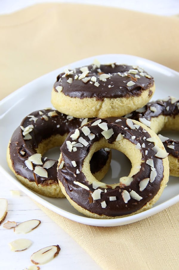 These Chocolate Glazed Almond Donuts are baked to perfect and topped with chocolate and almonds! They bake up in just about 10 minutes! | The Bitter Side of Sweet Chocolate Almond Glazed Donuts on white plate