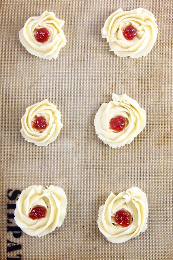 Raspberry Butter Cookies are sweet, simple, and perfect for gifting. Light, crisp butter cookies with a dollop of raspberry jam are great with a cup of tea!