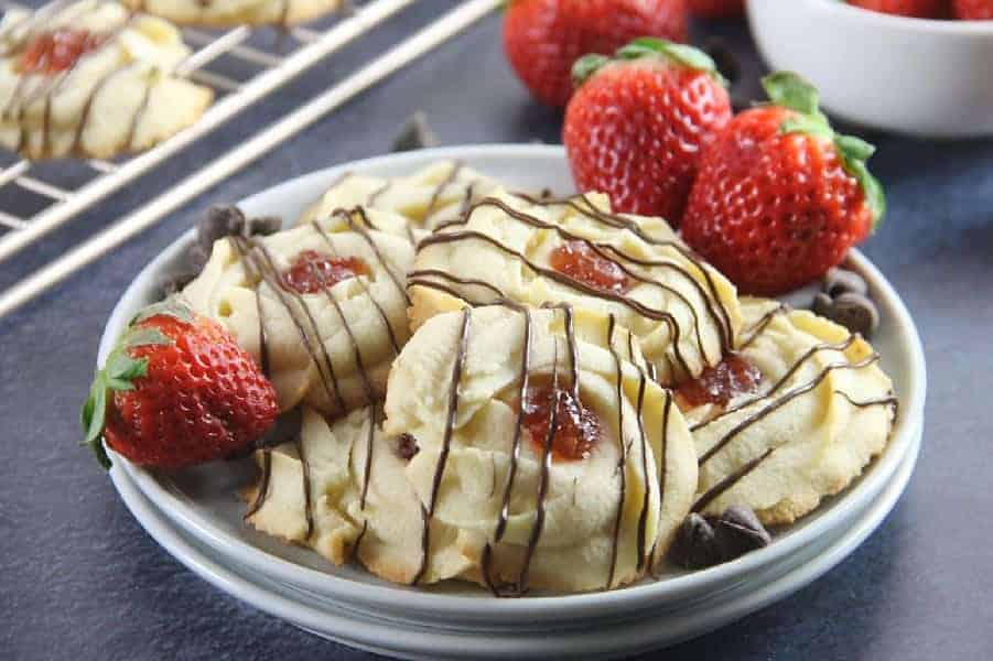 These Strawberry Chocolate Butter Cookies are a fun twist to the classic Italian Butter Cookie! So delicious with strawberry jam and chocolate drizzle! Strawberry Chocolate Butter Cookies on white plate