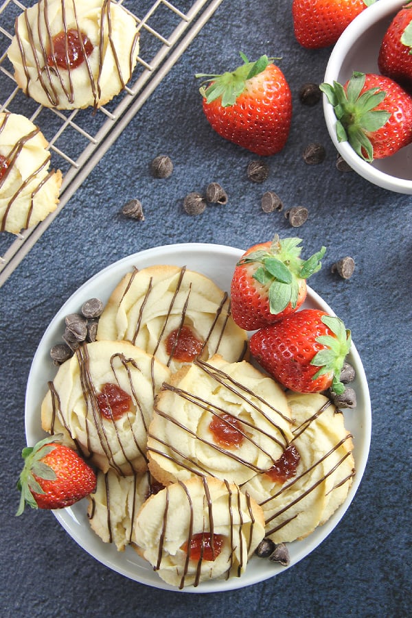 These Strawberry Chocolate Butter Cookies are a fun twist to the classic Italian Butter Cookie! So delicious with strawberry jam and chocolate drizzle! Strawberry Chocolate Butter Cookies on white plate