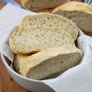 Homemade Italian Bread in gray bowl on brown cutting board