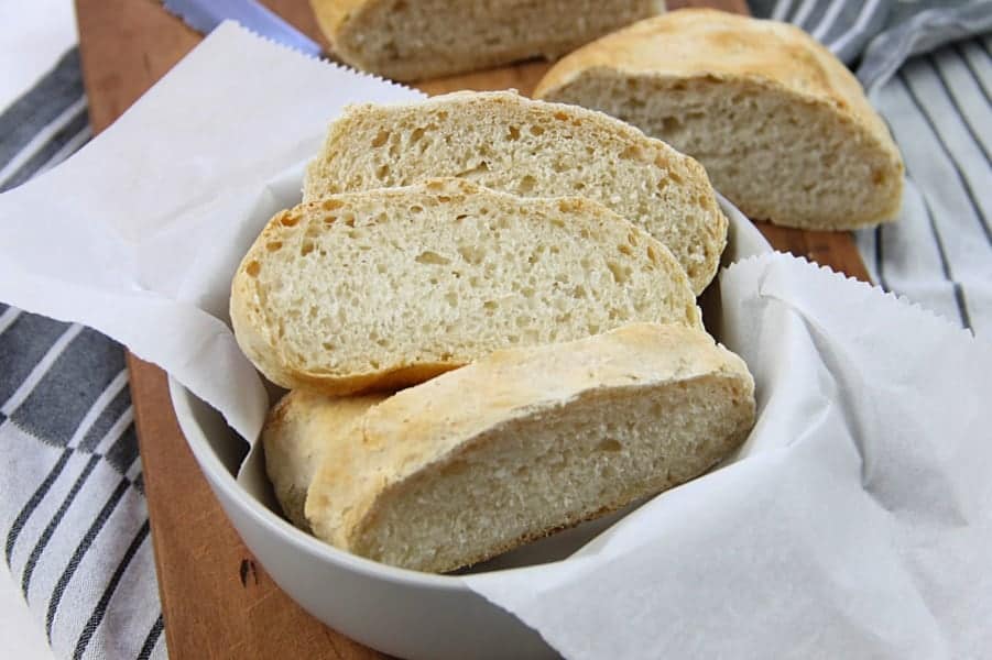 This Homemade Italian Bread is super easy to make with only 6 ingredients and very little time kneading it! Baked up in the oven for a perfect crispy bread! Homemade Italian Bread in gray bowl on brown cutting board