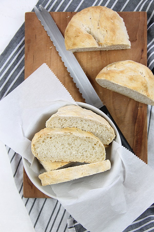 This Homemade Italian Bread is super easy to make with only 6 ingredients and very little time kneading it! Baked up in the oven for a perfect crispy bread! Homemade Italian Bread on cutting board with knife and bowl