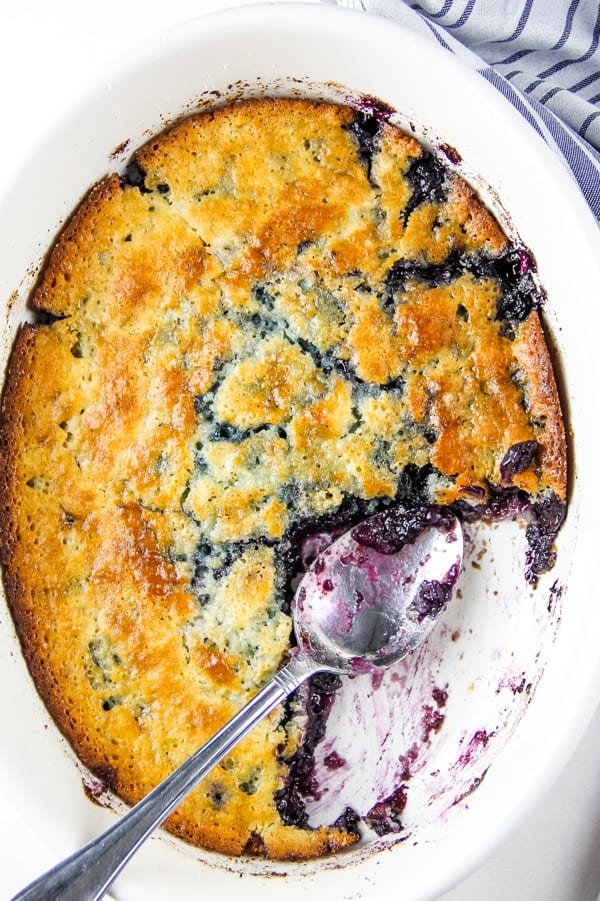 Easy Homemade Blueberry Cobbler! With an easy buttery crust mixed with fresh or frozen blueberries, this is the perfect fruit dessert! Blueberry Cobbler in white bowl with spoon