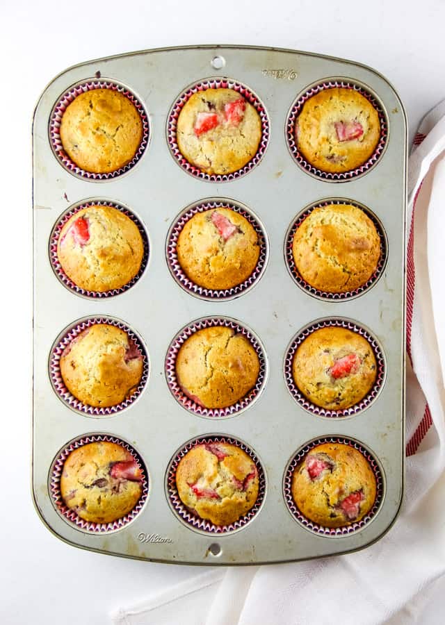 Strawberry Oatmeal Muffins are a hearty, soft breakfast muffin! Studded with fresh strawberries, these portable muffins will become a delicious favorite! Strawberry Oatmeal Muffins overhead view of twelve muffins in cupcake pan