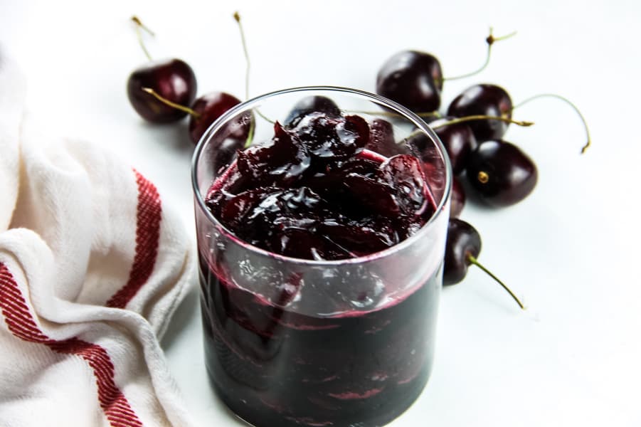 With 4 ingredients this Easy Cherry Compote is the best topping for putting on ice cream, pound cake, or even granola! Perfectly made with fresh cherries! Easy Cherry Compote in glass cup with fresh cherries in background