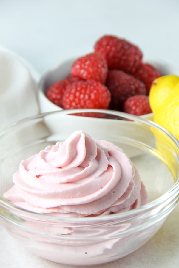 Easy 4 ingredient Lemon Raspberry Whipped Cream! A sweet homemade whipped cream filled with lemon and raspberry flavors! Perfect for topping on any dessert! Lemon Raspberry Whipped Cream in glass bowl