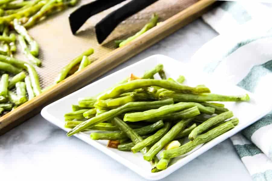 These easy sheet pan Roasted Green Beans are the simplest side dish ever! With just 4 ingredients and 20 minutes they will be cooked to perfection! Sheet Pan Roasted Green Beans on white plate