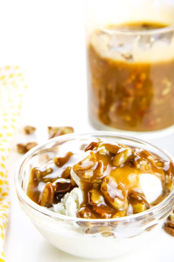 Easy Butter Pecan Sauce made with 6 ingredients! A creamy, gooey sauce filled with pecans and perfect topping for ice cream or any dessert! Butter Pecan Sauce in glass bowl with large cup of sauce in background