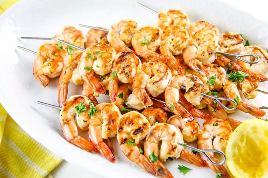 Easy Grilled Lemon Shrimp Skewers made with just 5 ingredients! Can be cooked on a grill or even in the oven! Grilled Lemon Shrimp Skewers on white plate with yellow towel topped with parsley