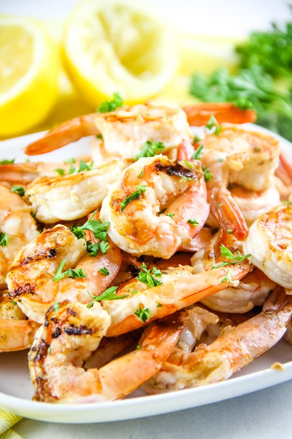 Easy Grilled Lemon Shrimp Skewers made with just 5 ingredients! Can be cooked on a grill or even in the oven! Grilled Lemon Shrimp Skewers with shrimp stacked on a white plate