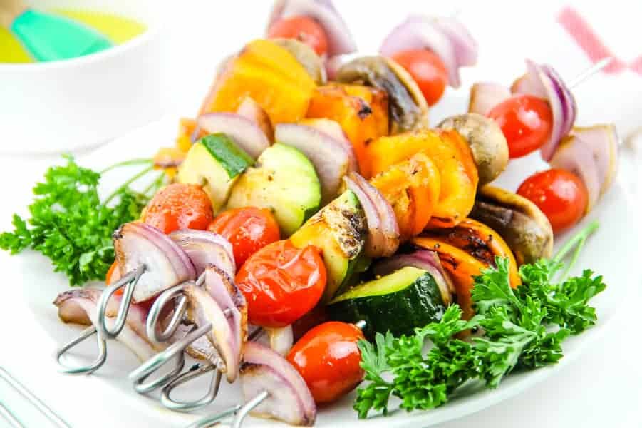 Easy Grilled Vegetable Skewers made with 5 different vegetables, flavored with salt, pepper and olive oil! Perfect for the grill or oven! Grilled Vegetable Skewers on white plate with parsley and bowl of olive oil in background