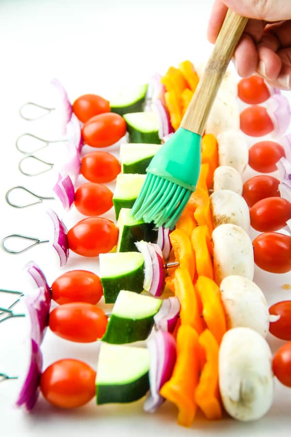 Easy Grilled Vegetable Skewers made with 5 different vegetables, flavored with salt, pepper and olive oil! Perfect for the grill or oven! Grilled Vegetable Skewers with green brush, brushing on oil