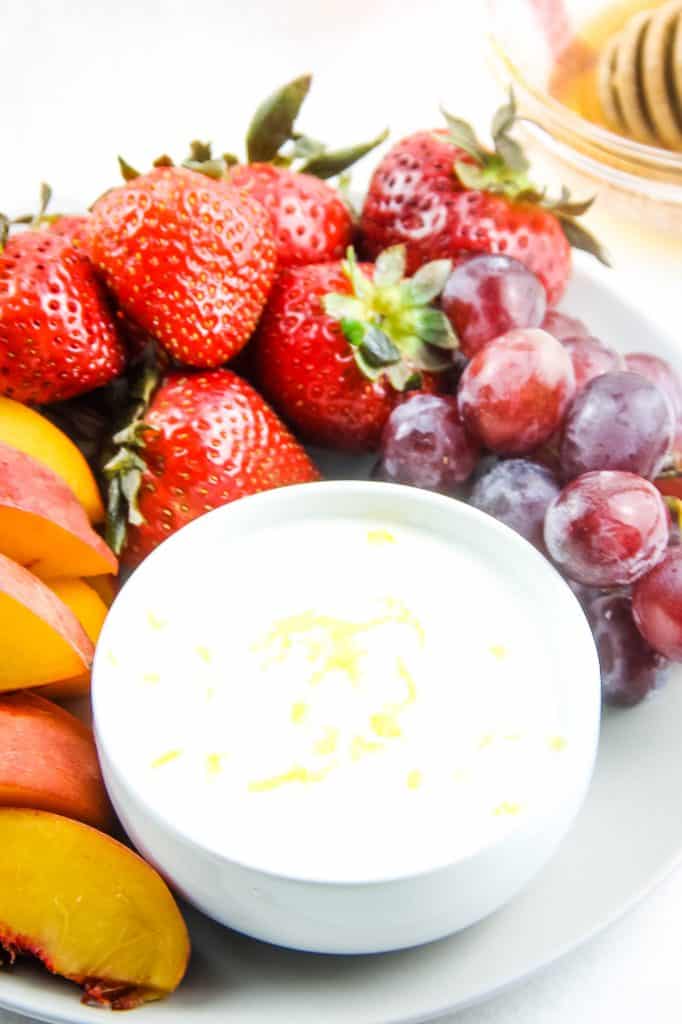 This Easy Honey Yogurt Dip is flavored with honey, lemon zest and vanilla! Top this homemade with granola or serve with fresh fruits! Honey Yogurt Dip on plate with fruit