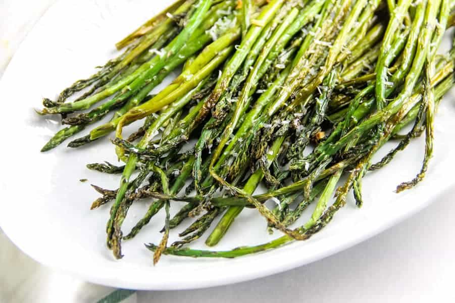 Easy Sheet Pan Roasted Asparagus coated in olive oil, fresh garlic and salt! This simple side dish is the easiest way to make asparagus! Sheet Pan Roasted Asparagus on white platter