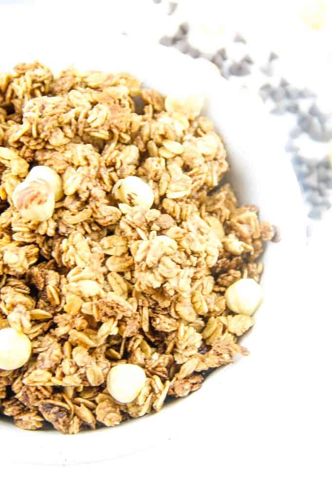 This Chocolate Hazelnut Granola is perfect for snacking! Made with nutella, oats, maple syrup and canola oil! Simple and easy! Chocolate Hazelnut Granola in bowl topped with fresh hazelnuts