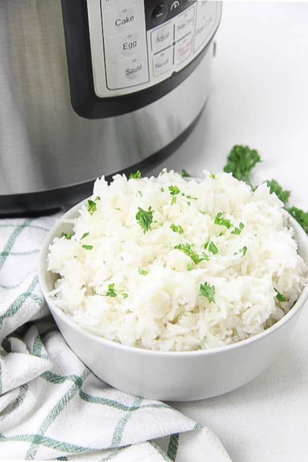 The EASIEST side dish to make! This Instant Pot Basmati Rice will be one that you make over and over again! Instant Pot Basmati Rice in white bowl topped with parsley