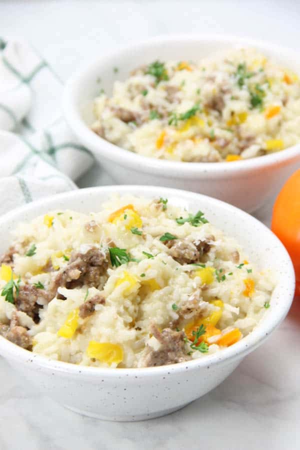 This Instant Pot Sausage and Peppers Risotto is perfect for a quick meal! Filled with Italian sausage and colorful peppers! Instant Pot Sausage and Peppers Risotto in bowl topped with green parsley