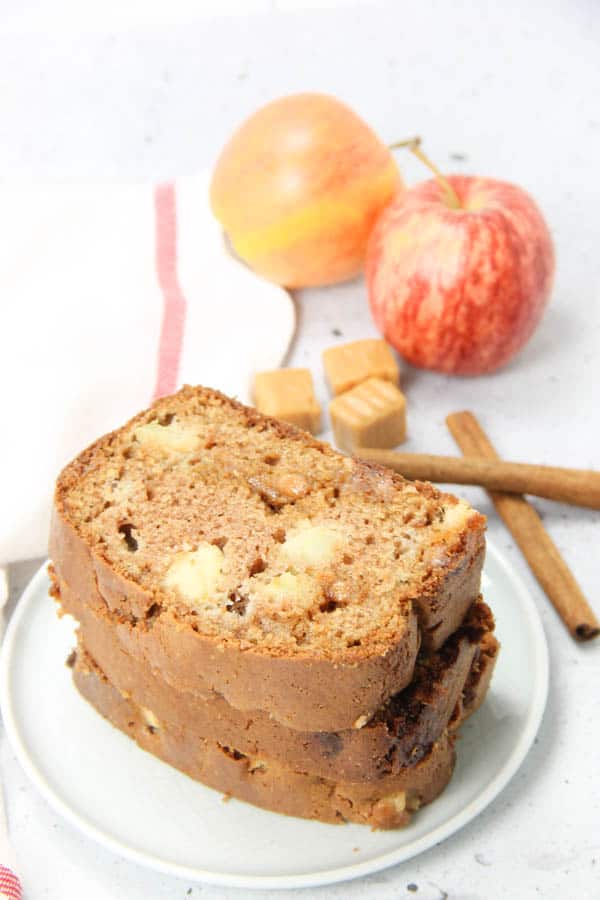 using all whole wheat flour, dried cranberries and pumpkin seeds. Caramel Apple Bread stacked on white plate