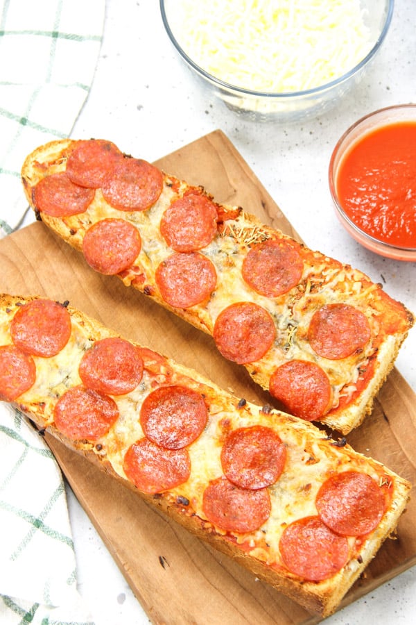 Super simple Pepperoni French Bread Pizza! Bakes up in 15 minutes! Cheesy, full of spices with a crunchy french bread crust! Pepperoni French Bread Pizza on cutting board
