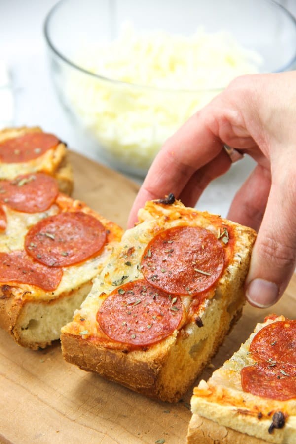 Super simple Pepperoni French Bread Pizza! Bakes up in 15 minutes! Cheesy, full of spices with a crunchy french bread crust! Pepperoni French Bread Pizza sliced on cutting board