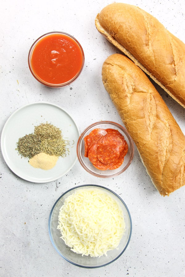 Super simple Pepperoni French Bread Pizza! Bakes up in 15 minutes! Cheesy, full of spices with a crunchy french bread crust! Pepperoni French Bread Pizza ingredients on white background