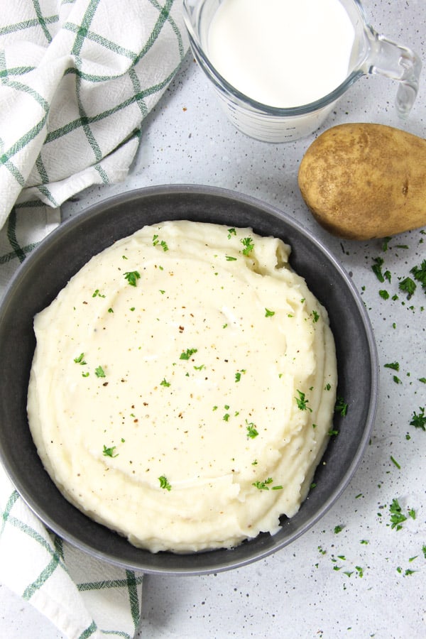 Pressure Cooker Mashed Potatoes with Gravy is an easy side dish! With creamy potatoes and a white gravy, it's ready in no time! Pressure Cooker Potatoes with Gravy in gray bowl topped with parsley
